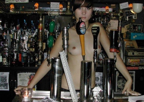 Attractive Bartender with Sexy Smile and Cleavage in Tight Uniform - Hot Barmaid Serving Drinks in Pub